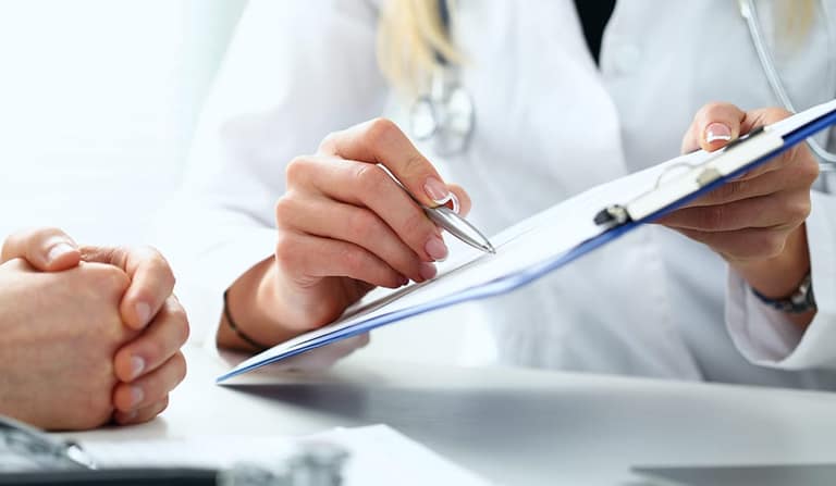 A doctor pointing a pen at a clipboard