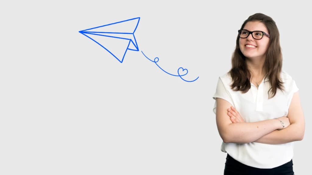 A smiling young woman beside a hand-drawn paper airplane