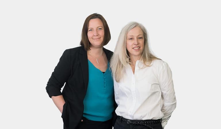 Two women standing side by side, smiling