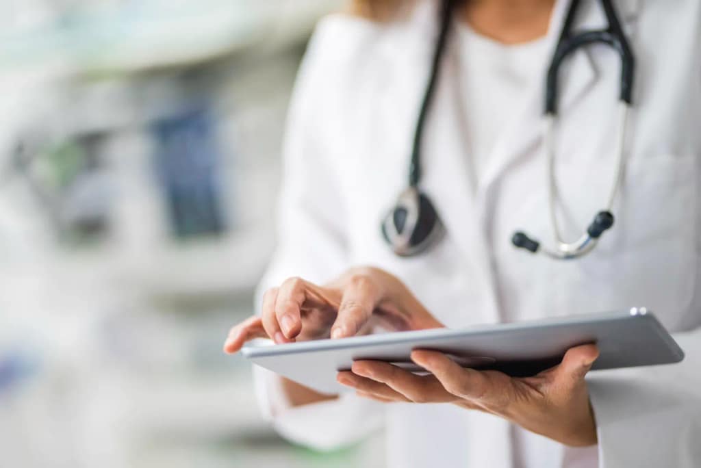 A doctor with a stethoscope using a tablet